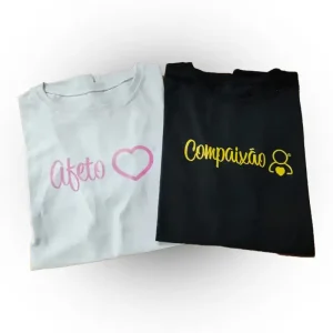 Camisetas Afeto, branca com o texto Afeto em rosa, e compaixão preta com o texto em amarelo
